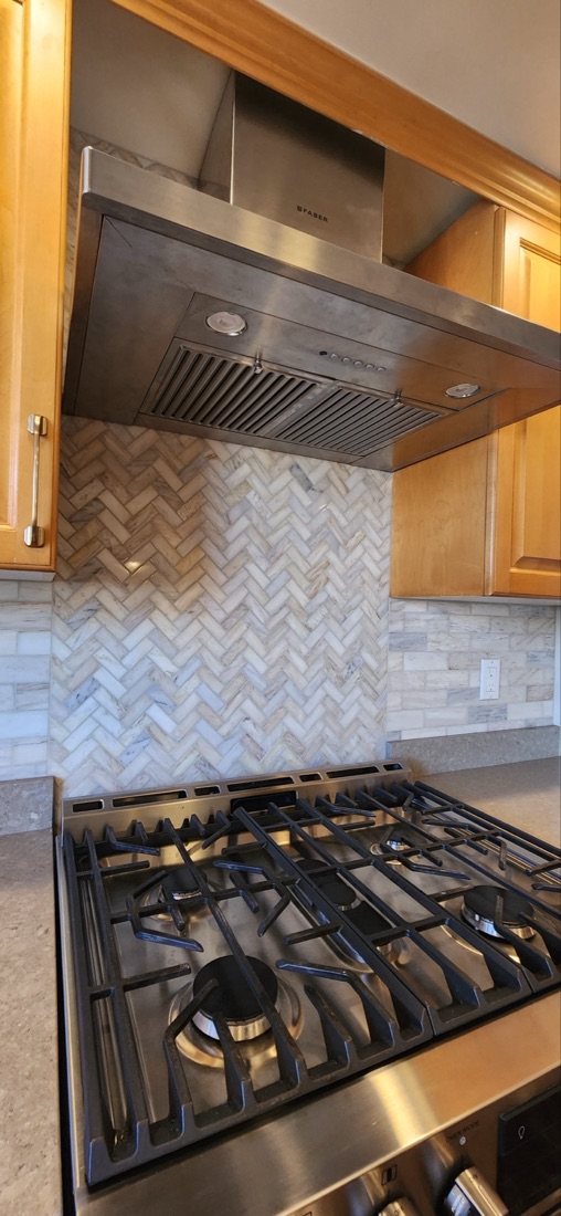 Herringbone tile feature behind a kitchen range with a horizontal tiled backsplash on the adjoining wall